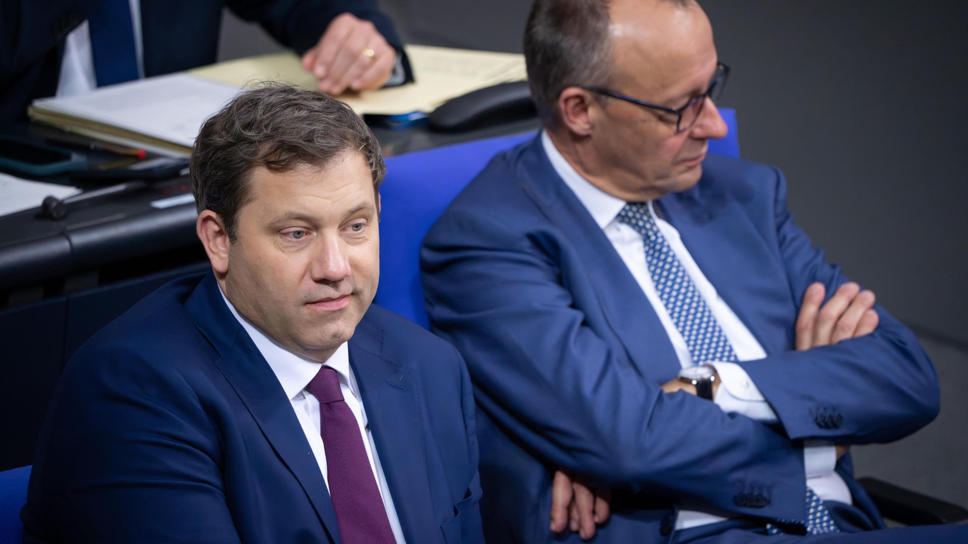 Lars Klingbeil und Friedrich Merz sitzen auf der Regierungsbank im Deutschen Bundestag und schauen in unterschiedliche Richtungen.