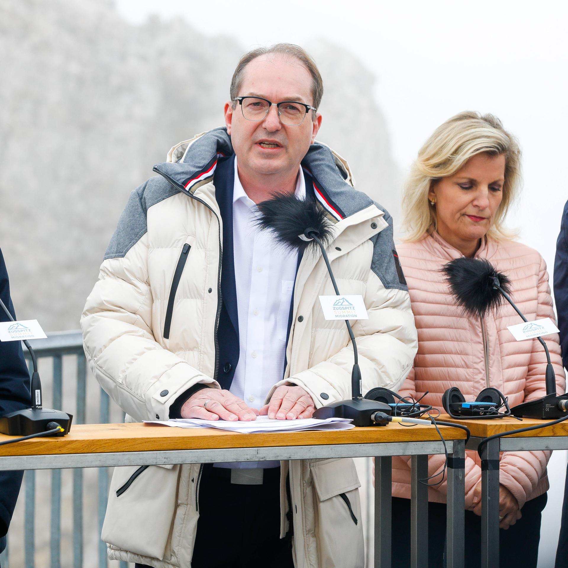 Bundesinnenminister Alexander Dobrindt bei der Pressekonferenz auf der Zugspitze; er trägt einen Anorak und spricht in ein Mikrofon. Neben ihm stehen weitere Personen.