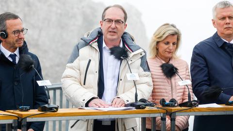 Bundesinnenminister Alexander Dobrindt bei der Pressekonferenz auf der Zugspitze; er trägt einen Anorak und spricht in ein Mikrofon. Neben ihm stehen weitere Personen.