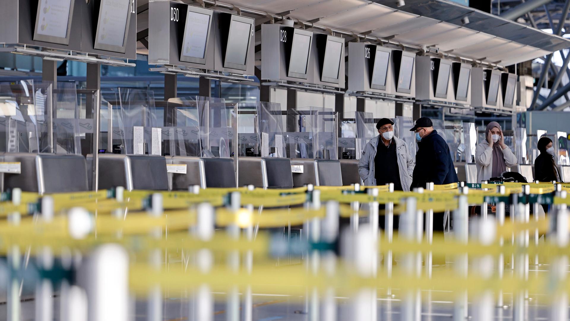 Leerer Flughafen-Schalter - nur vereinzelt sind Menschen mit Mund-Nasen-Maske zu sehen.