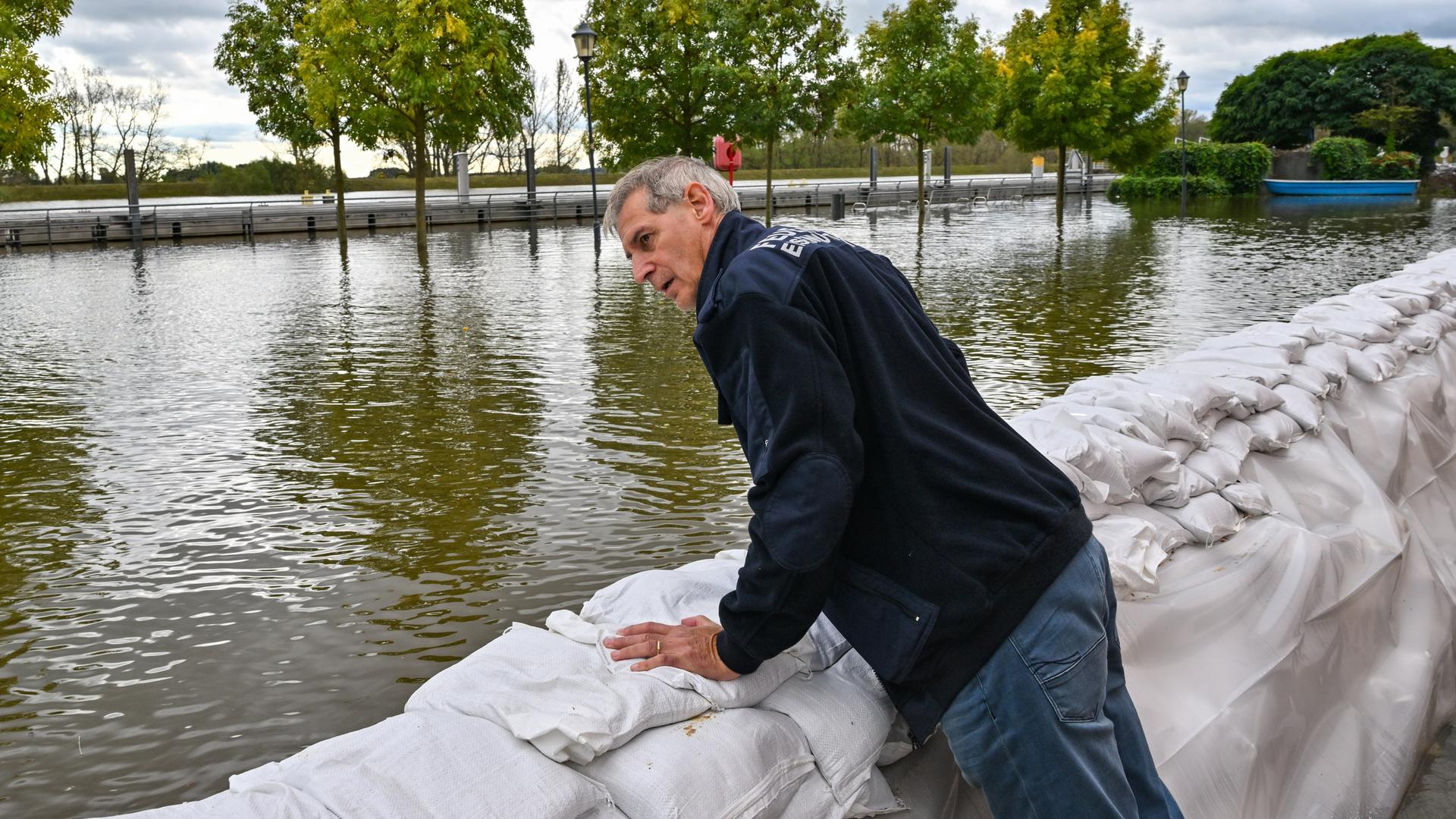 Frank Balzer (SPD), Bürgermeister von Eisenhüttenstadt, blickt über einen Wall aus Sandsäcken auf das Hochwasser des Flusses Oder, das bereits Straßen überflutet hat. 