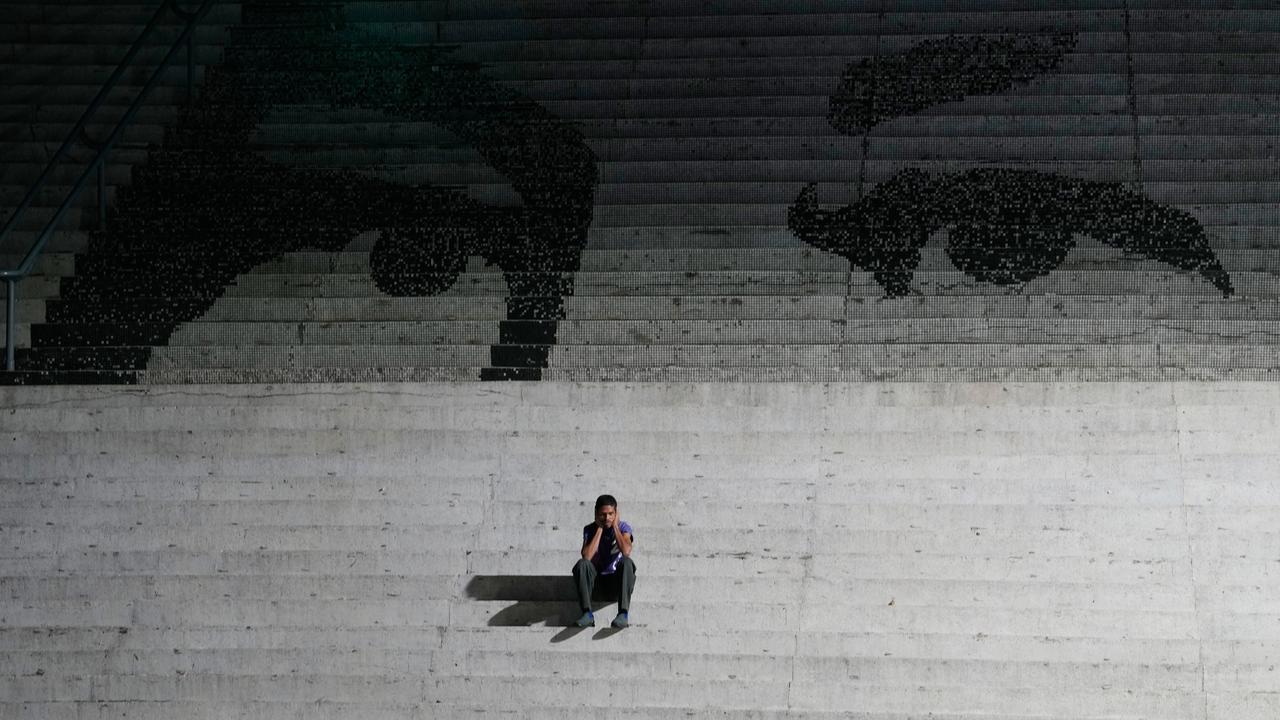 Ein Mann sitzt auf einer Treppe. Auf den Treppen ist ein Graffiti, das die Augen des verstorbenen venezuelanischen Präsidenten Hugo Chavez zeigen.