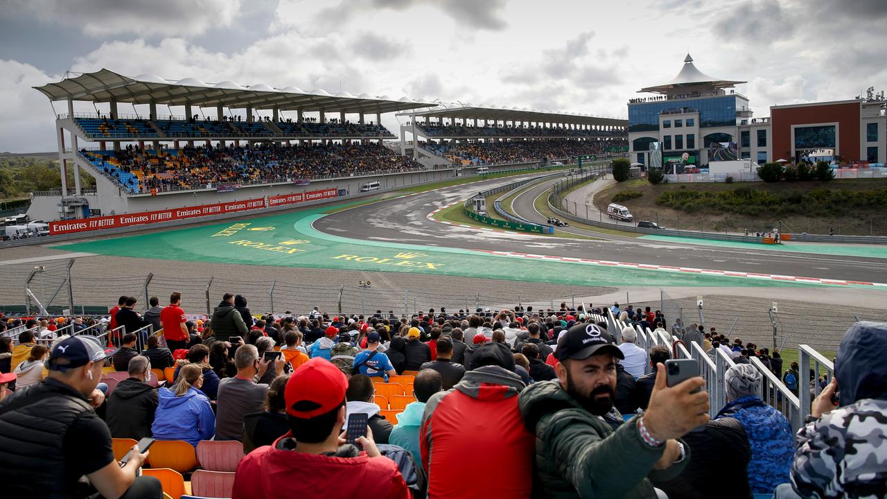 Ein Formel 1-Rennen im Jahr 2021 in Istanbul Park. Man sieht einen Teil der Rennstrecke und im Vordergrund Zuschauer. Ein Zschauer macht ein Selfie.
