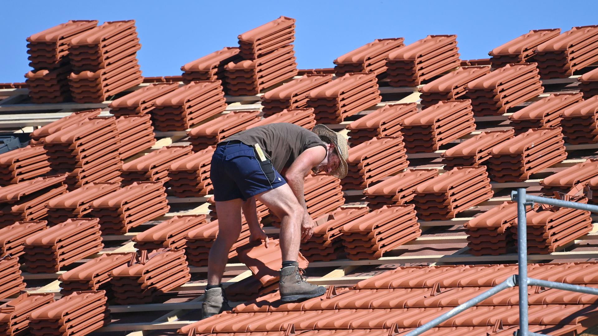 Ein Dachdecker arbeitet auf einem Hausdach bei heissen Somertemperaturen.