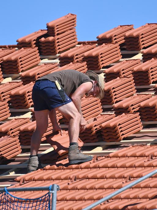 Ein Dachdecker arbeitet auf einem Hausdach bei heissen Somertemperaturen.