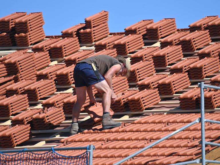 Ein Dachdecker arbeitet auf einem Hausdach bei heissen Somertemperaturen.