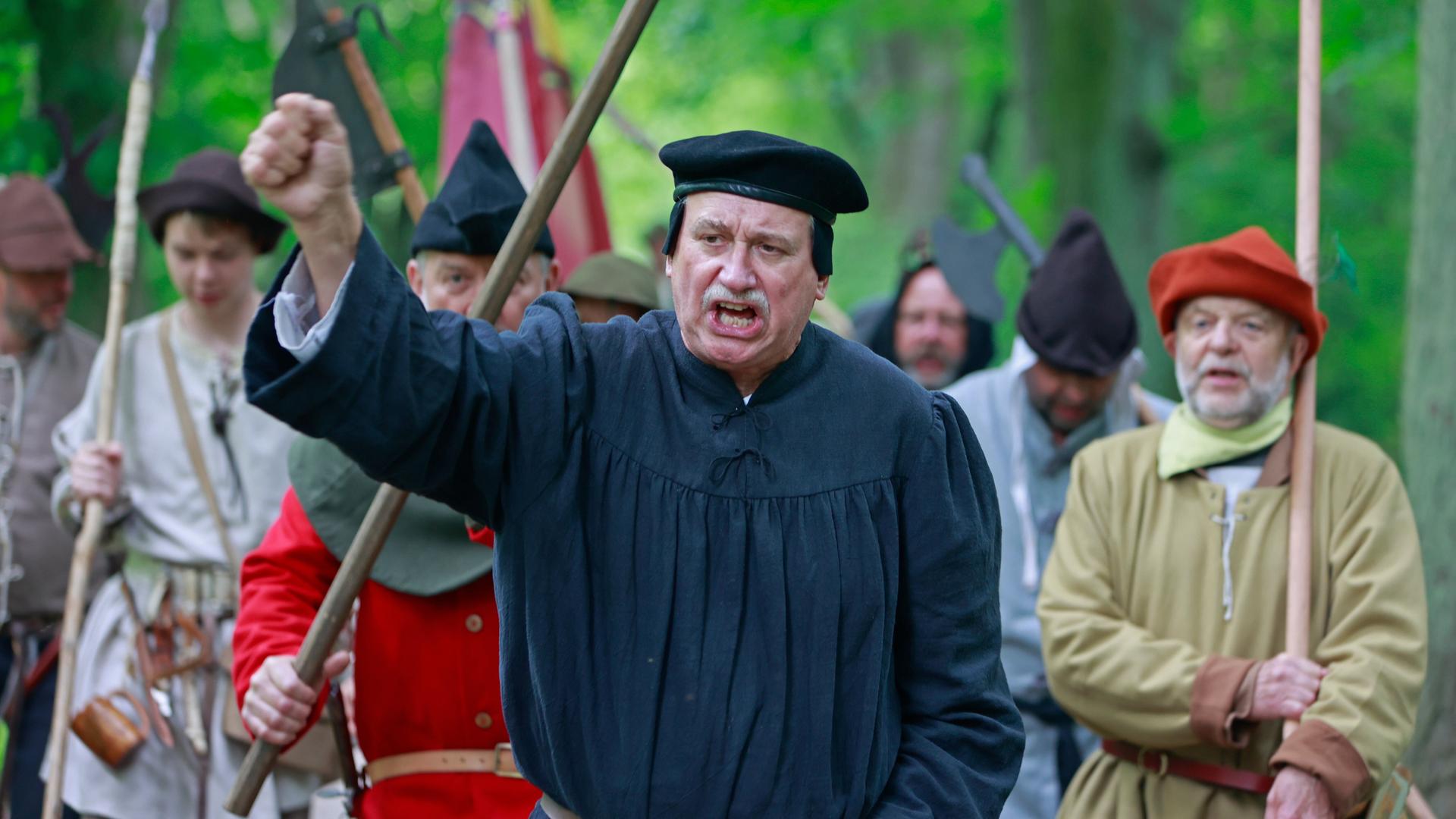 Als Bauern kostümierte Darsteller eines historischen Bauernzuges ziehen mit Thomas Müntzer Darsteller Roland Sölle (Mitte) durch ein Waldstück in Sondershausen zur Nachstellung der Bauernschlacht vor 500 Jahren in Bad Frankenhausen. 