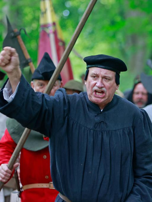 Als Bauern kostümierte Darsteller eines historischen Bauernzuges ziehen mit Thomas Müntzer Darsteller Roland Sölle (Mitte) durch ein Waldstück in Sondershausen zur Nachstellung der Bauernschlacht vor 500 Jahren in Bad Frankenhausen. 