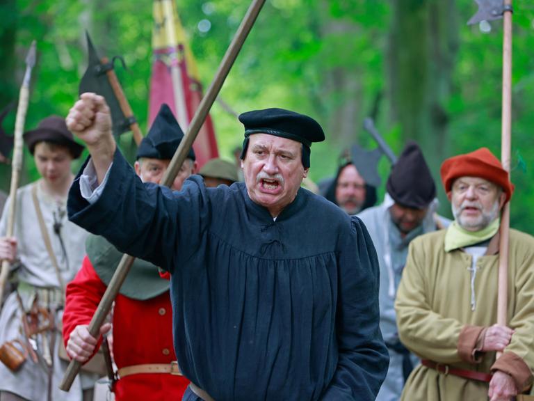 Als Bauern kostümierte Darsteller eines historischen Bauernzuges ziehen mit Thomas Müntzer Darsteller Roland Sölle (Mitte) durch ein Waldstück in Sondershausen zur Nachstellung der Bauernschlacht vor 500 Jahren in Bad Frankenhausen. 