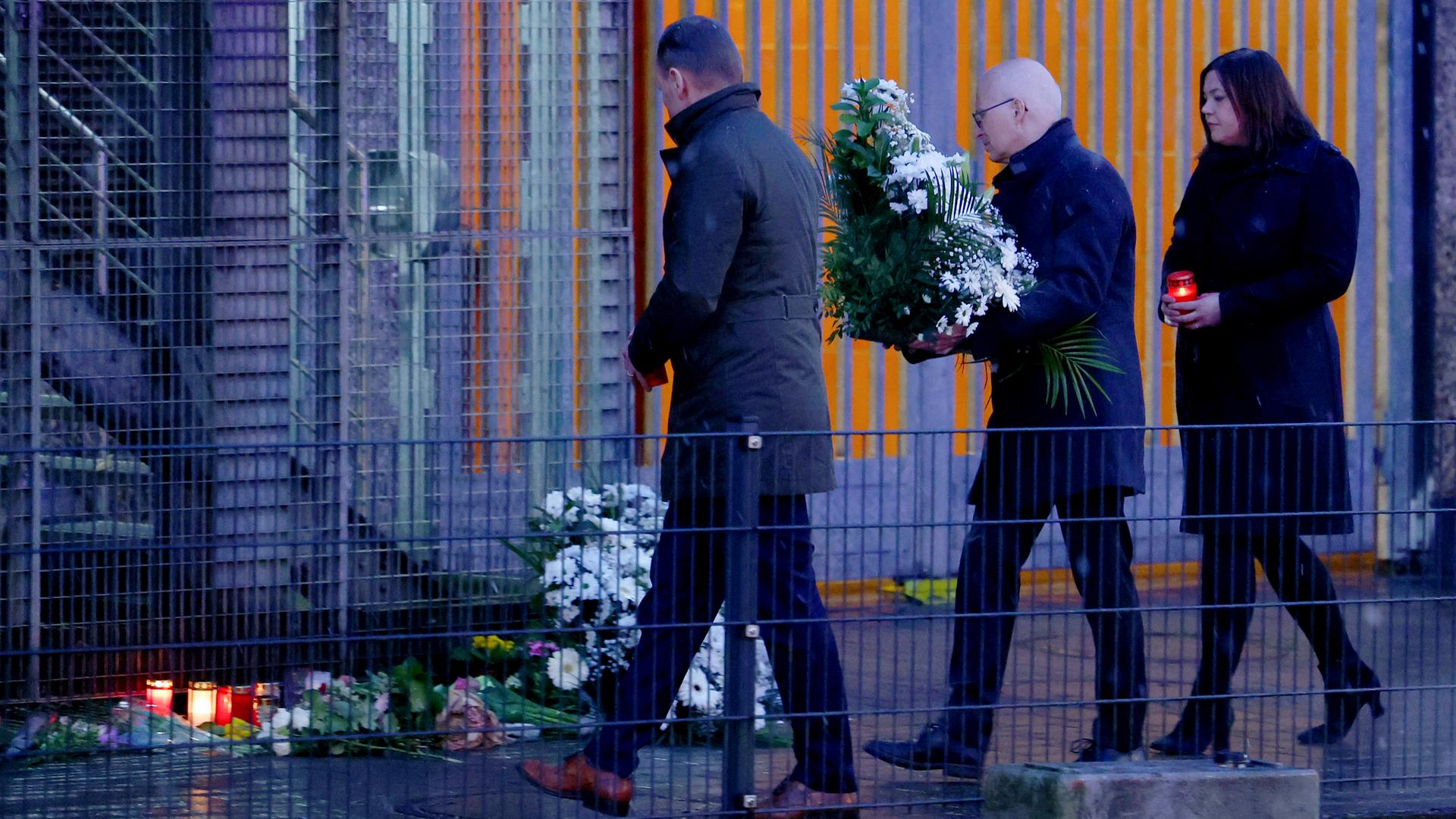 Hamburgs Erster Bürgermeister Tschentscher (Mitte) legt mit der Zweiten Bürgermeisterin Fegebank (rechts) Blumen am Tatort des Amoklaufs nieder.