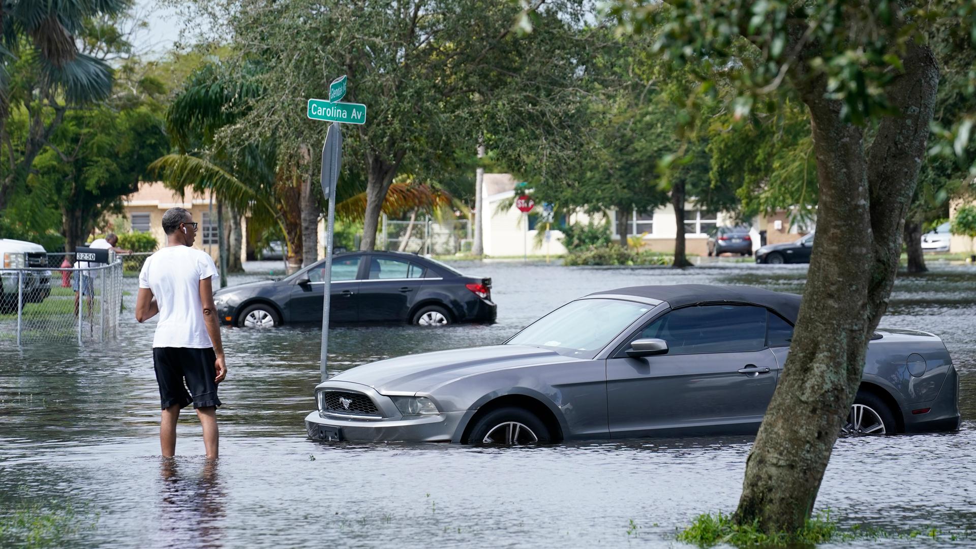 Autos und Menschen in Florida stehen nach einer Überflutung im Wasser.