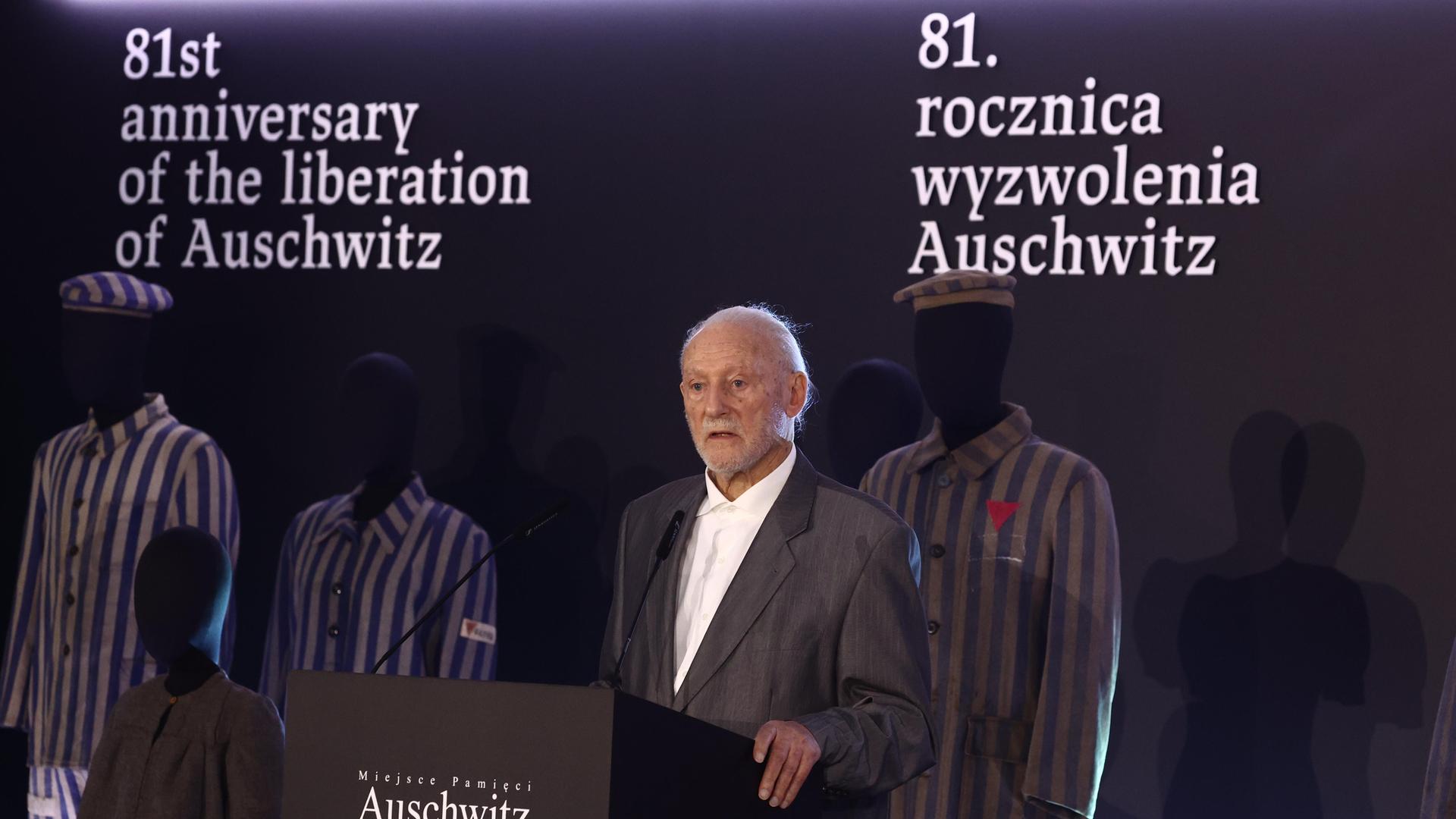Der Holocaust-Überlebende, Bernard Offen, steht bei einer Gedenkfeier zum Jahrestag der Befreiung des Vernichtungslagers Auschwitz-Birkenau hinter einem Rednerpult. Er steht vor menschlichen Puppen, die Häftlingskleidung tragen.
