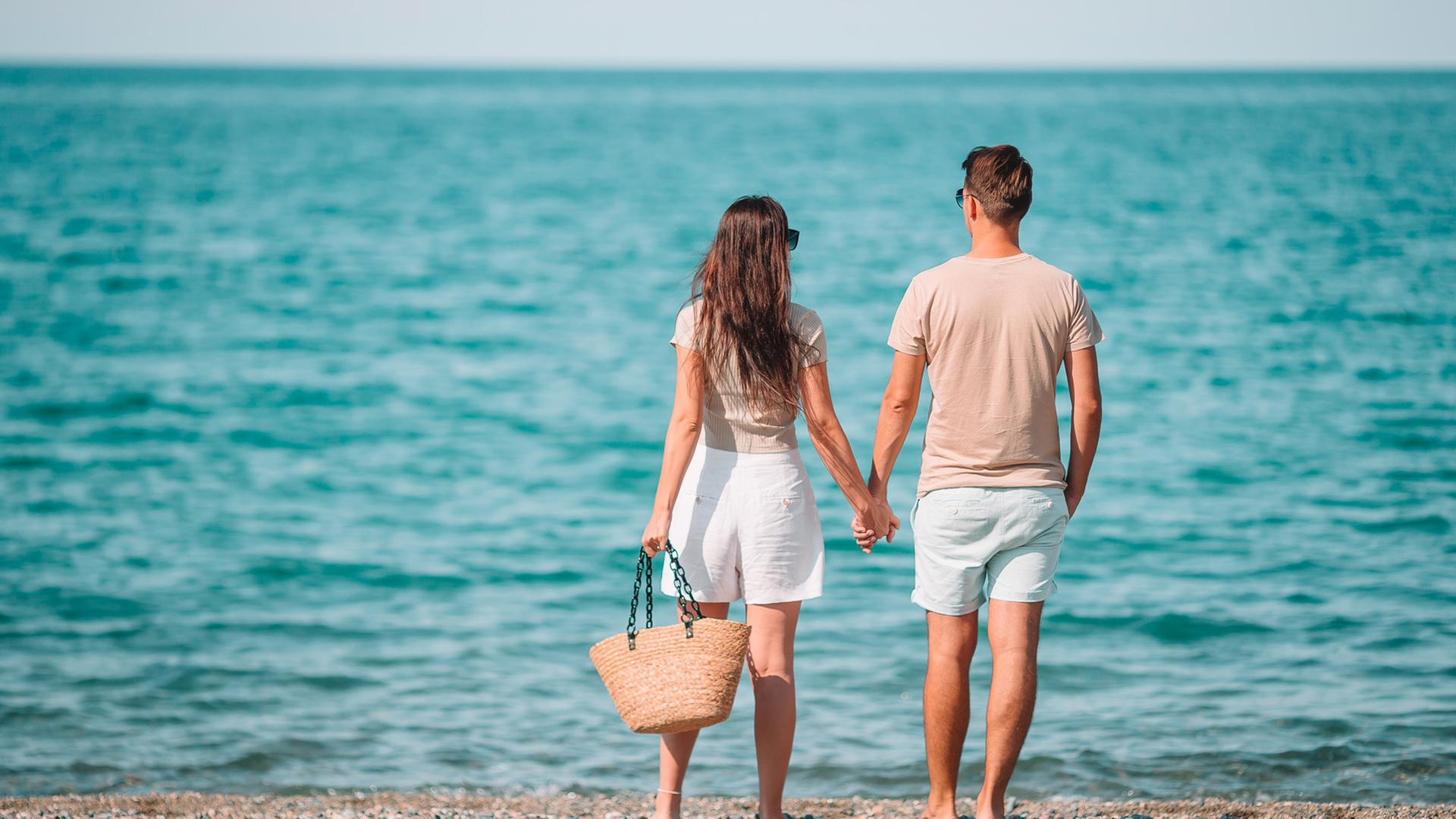 Ein junges Paar blickt auf das Meer im Sommer. 