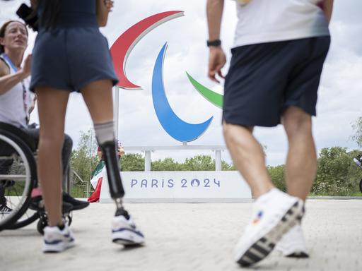 Sportlerinnen und Sportler vor dem Logo der Paralympics