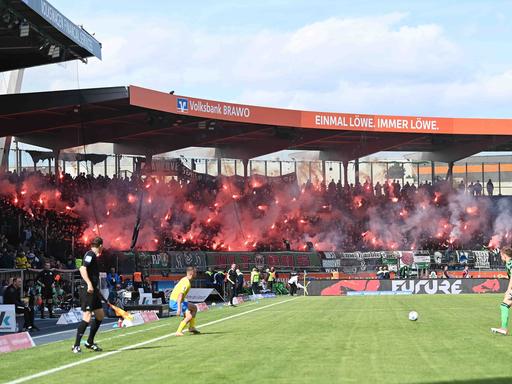 Blick in das Stadion von Eintracht Braunschweig. Im Hintergrund zünden Hannovers Fans Pyrotechnik.