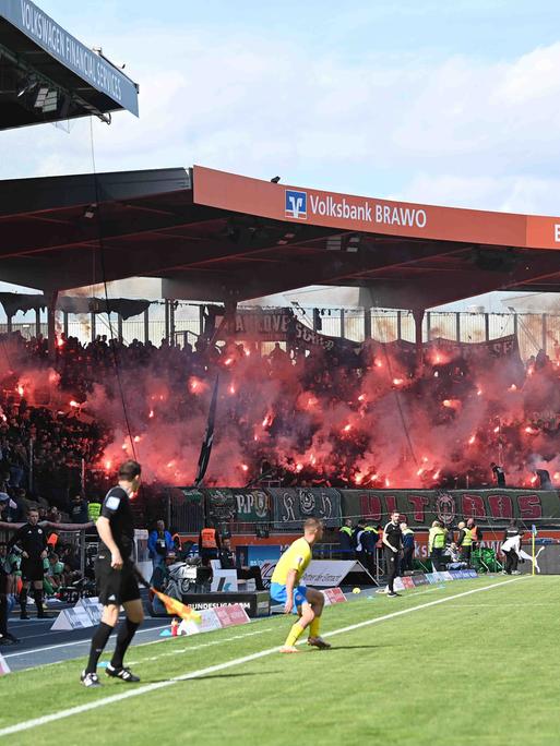 Blick in das Stadion von Eintracht Braunschweig. Im Hintergrund zünden Hannovers Fans Pyrotechnik.