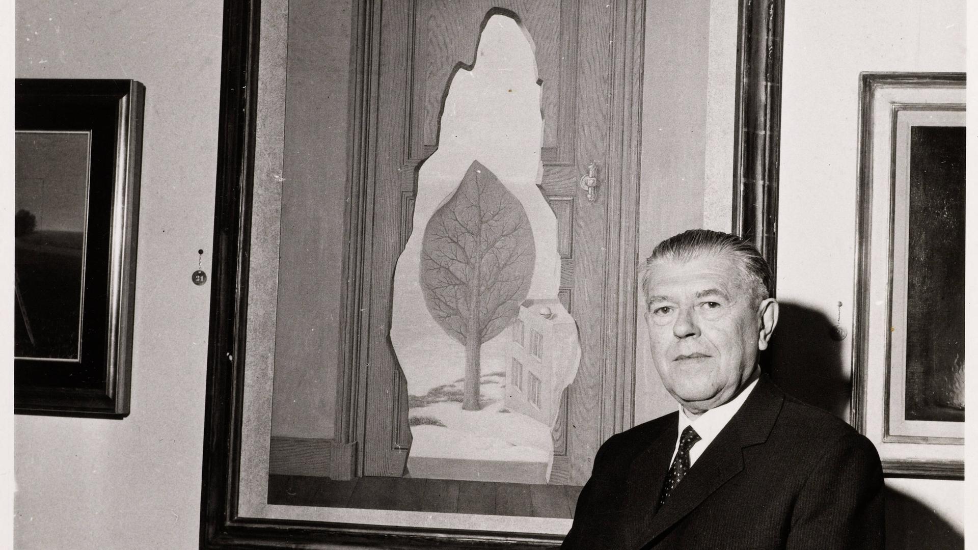 Der Künstler René Magritte steht vor einem seiner Gemälde. Der Künstler René Magritte steht vor einem seiner Gemälde.