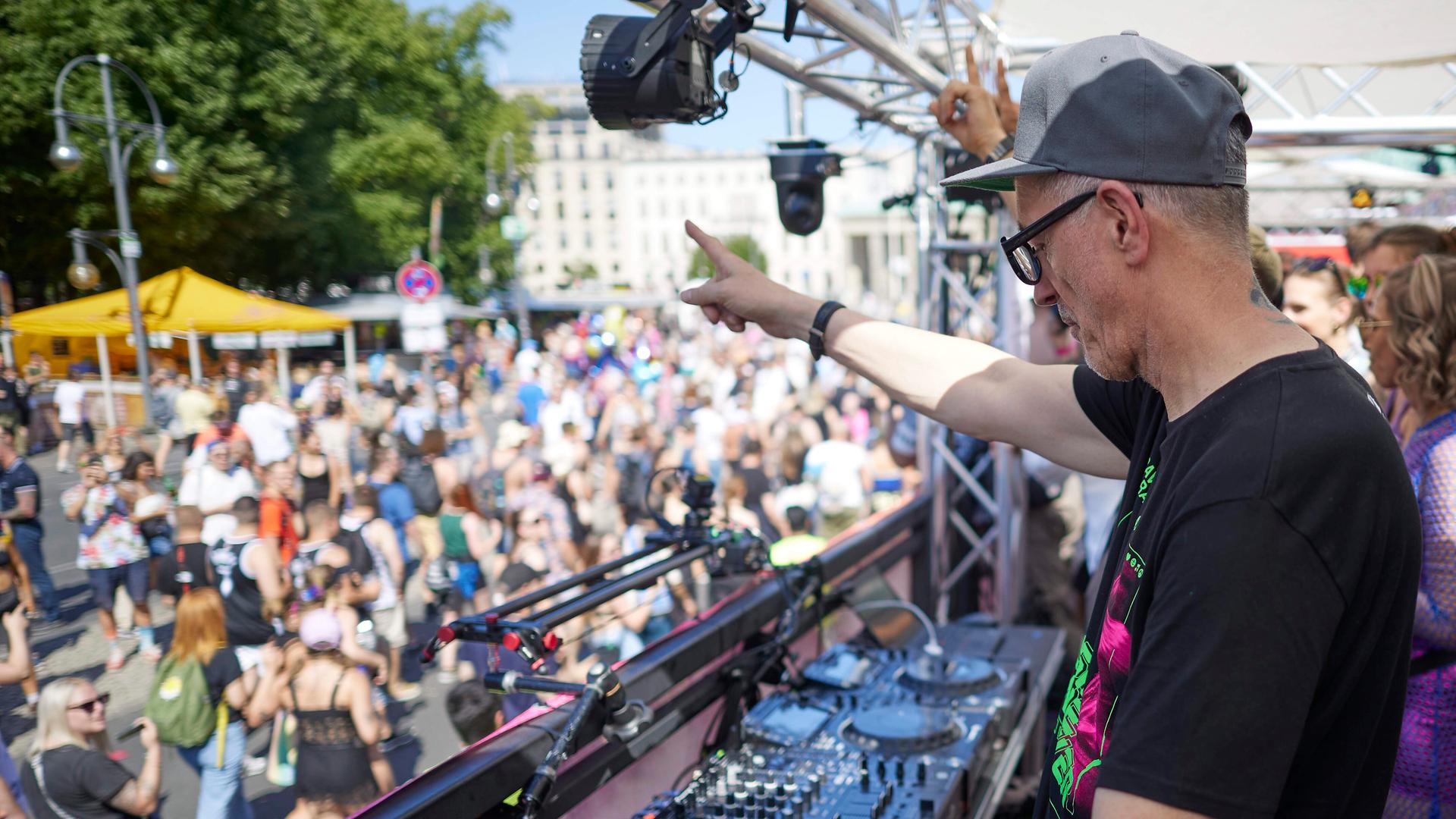 Dr. Motte steht tanzend bei der "Rave the Planet"-Technoparade auf der Straße des 17 Juni auf einem der Wagen. Im Hintergrund ist unscharf eine tanzende Menge zu sehen, die Sonne scheint von einem wolkenlosen Himmel. Aufnahme vom 08.07.2023.