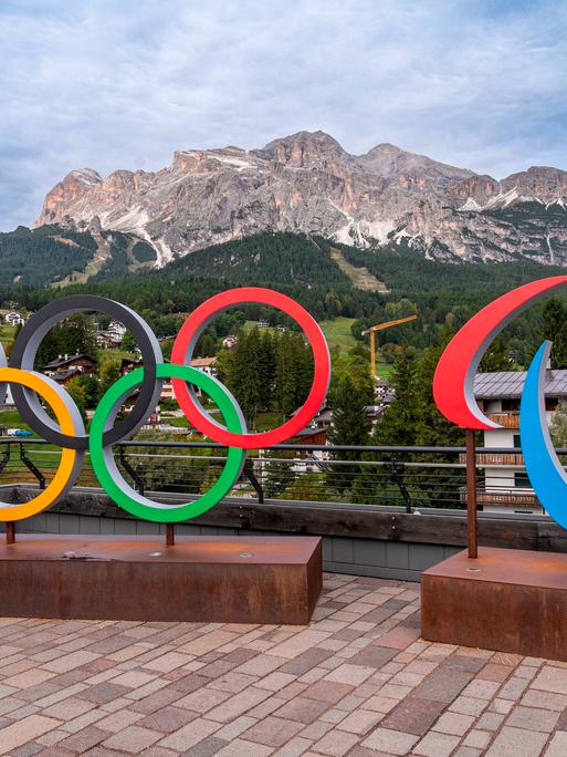 Olympische Ringe vor einem Bergpanaorama.