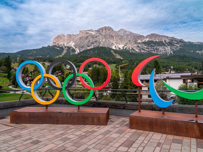 Olympische Ringe vor einem Bergpanaorama.
