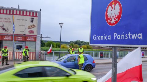 Das Bild zeigt polnische Grenzschützer, die die Insassen eines Kleinwagens kontrollieren. 