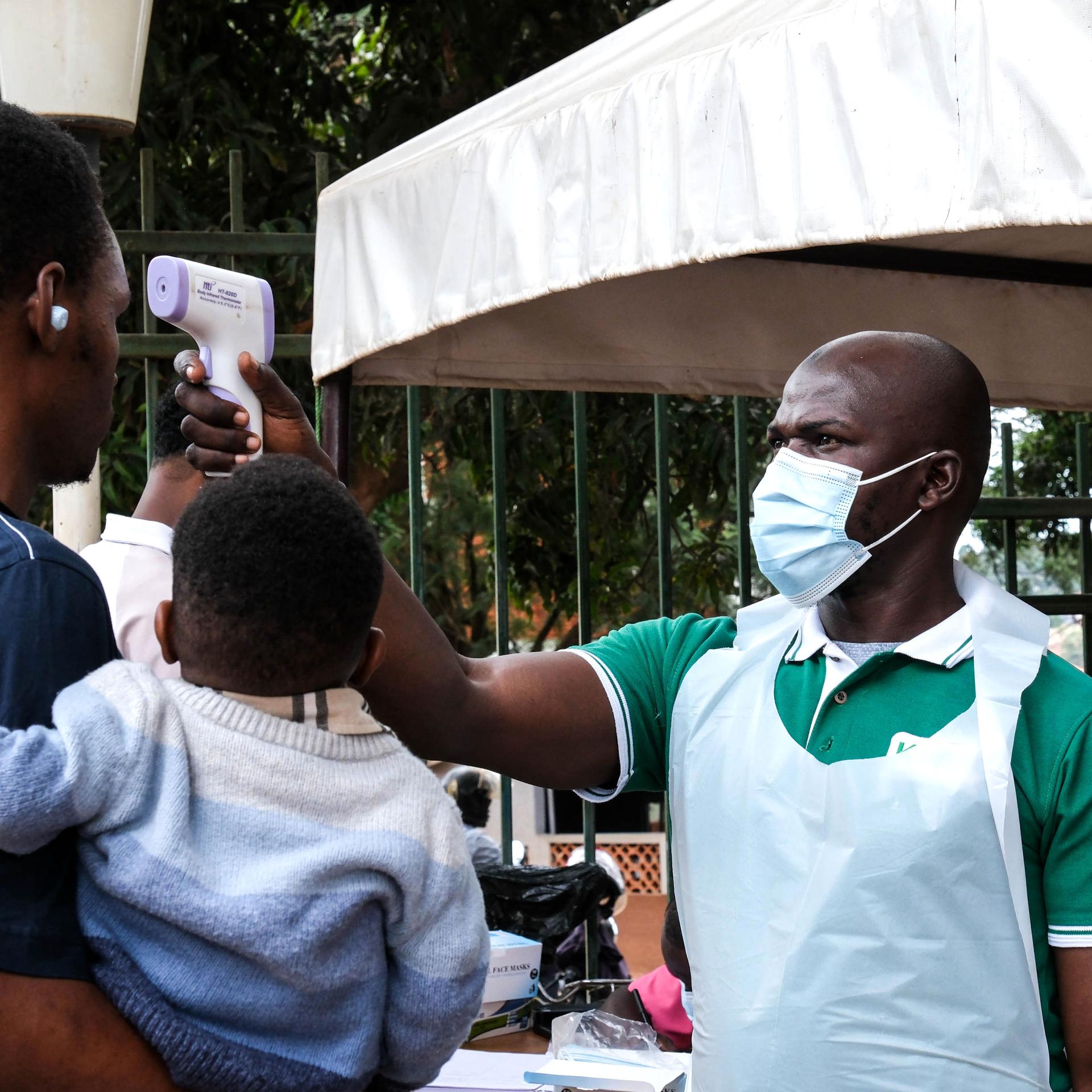 Ein Gesundheitsbeamter untersucht Menschen mit einem Thermometer vor dem Kibuli Muslim Hospital in Kampala. 