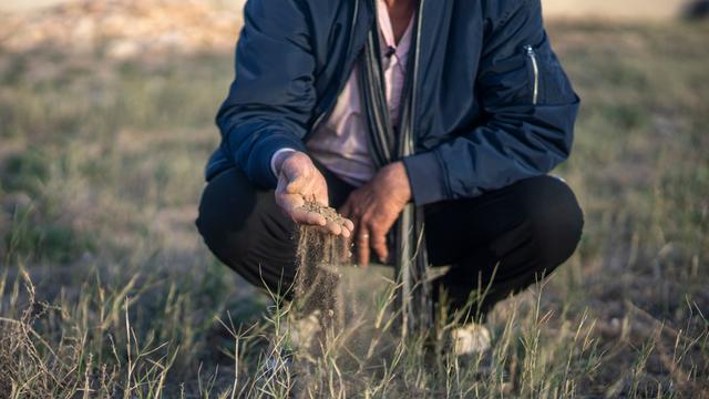 Mimoun Nadori untersucht mit seinen Händen den Boden seiner von Dürre heimgesuchten Felder im Norden Marokkos. 