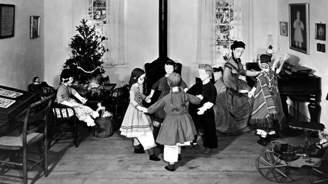 Diorama des ersten amerikanischen Kindergartens, der 1856 von Margarethe Meyer-Schurz in Watertown, Wisconsin in den USA eröffnet wurde. Kinderpuppen tanzen im Kreis vor einem Ofen, im Hintergrund steht ein geschmückter Weihnachtsbaum. Diorama des ersten amerikanischen Kindergartens, der 1856 von Margarethe Meyer-Schurz in Watertown, Wisconsin in den USA eröffnet wurde. Kinderpuppen tanzen im Kreis vor einem Ofen, im Hintergrund steht ein geschmückter Weihnachtsbaum.