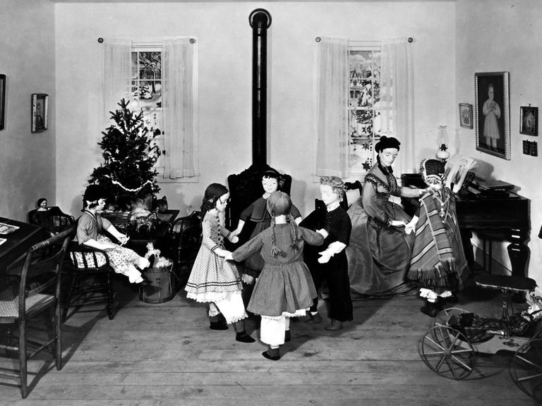 Diorama des ersten amerikanischen Kindergartens, der 1856 von Margarethe Meyer-Schurz in Watertown, Wisconsin in den USA eröffnet wurde. Kinderpuppen tanzen im Kreis vor einem Ofen, im Hintergrund steht ein geschmückter Weihnachtsbaum.
