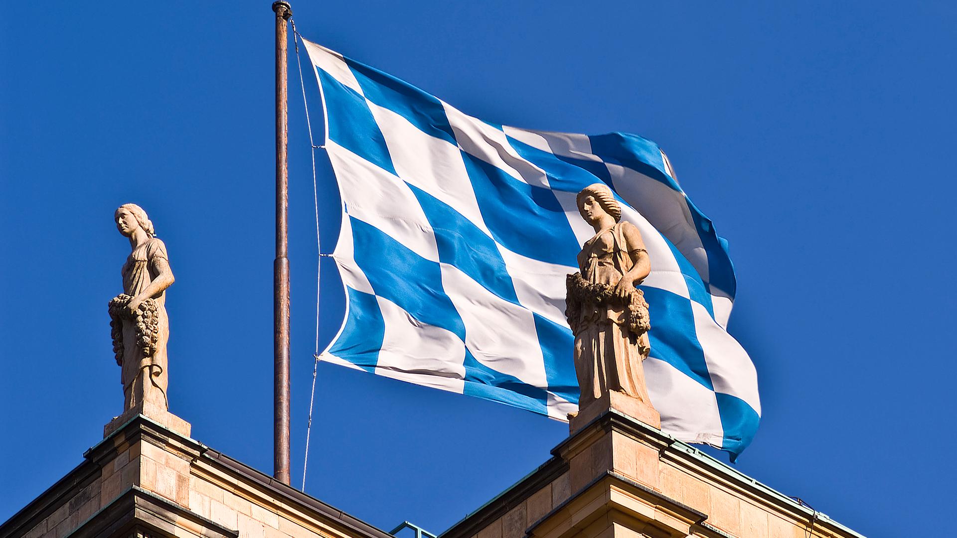 Die bayerische Landesflagge weht auf dem Landtagsgebäude, daneben die Bavaria