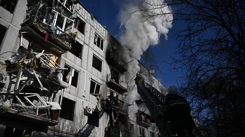 Die Feuerwehr versucht einen Wohnblock mit zerstörten Balkons zu löschen, aus dem eine Rauchwolke hoch aufsteigt.
