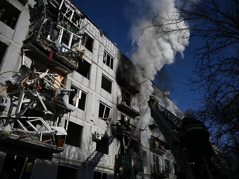 Die Feuerwehr versucht einen Wohnblock mit zerstörten Balkons zu löschen, aus dem eine Rauchwolke hoch aufsteigt.