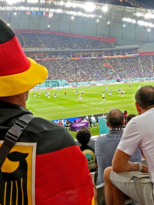 Deutsche Fans beobachten auf der Tribüne das ersten Vorrundenspiel zwischen Deutschland und Japan bei der Fußball-Weltmeisterschaft in Katar