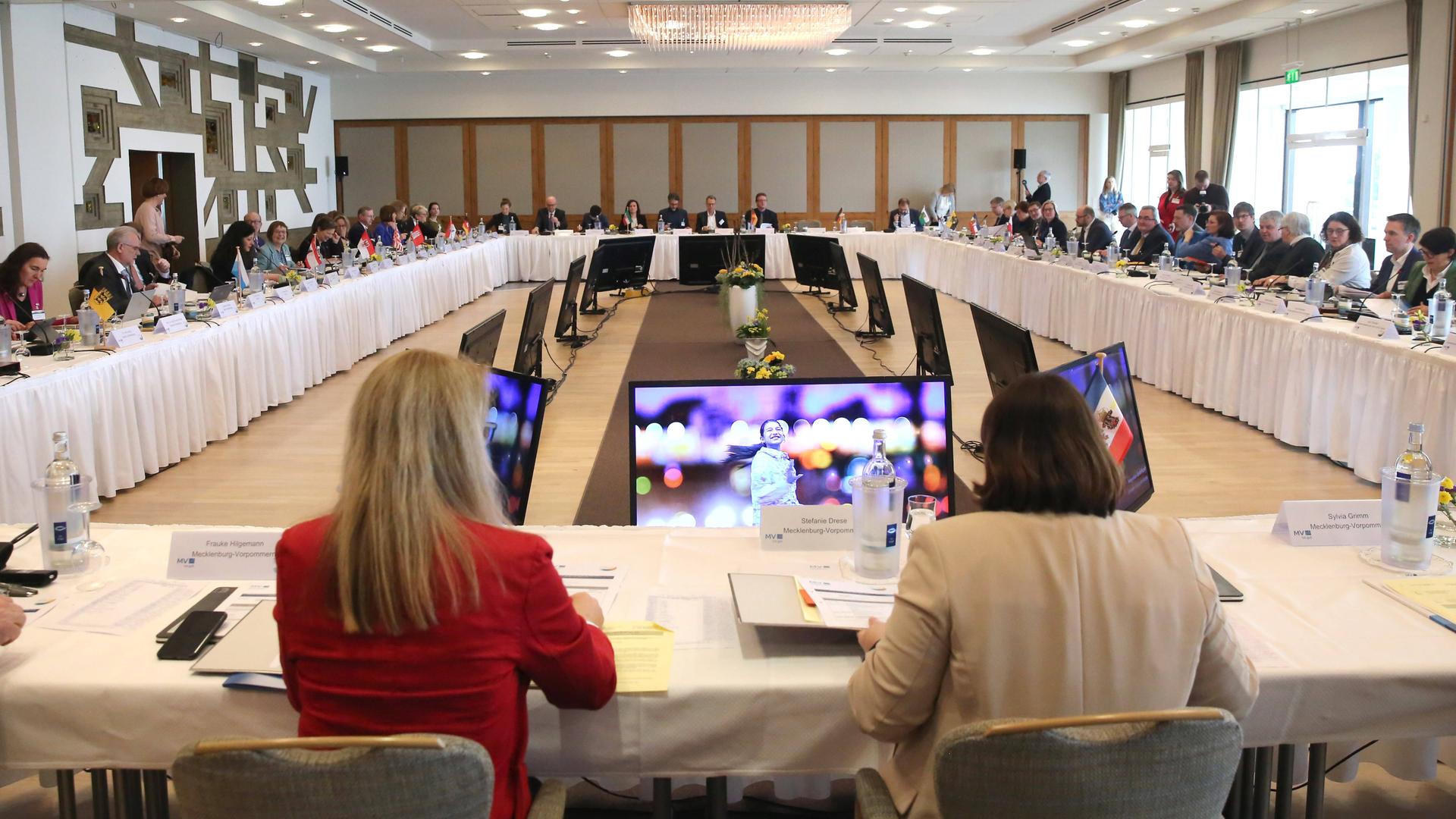 Blick auf die Integrationsministerkonferenz der Bundesländer. Um einen großen rechteckigen Tisch sitzen alle Beteiligten der Länder.