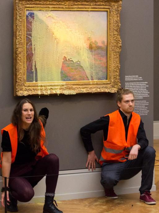 Klimaaktivisten der Gruppe "Letzte Generation" haben sich unter dem Monet-Gemälde, das sie mit Kartoffelbrei beworfen haben, festgeklebt.