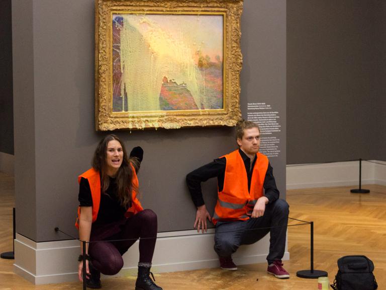 Klimaaktivisten der Gruppe "Letzte Generation" haben sich unter dem Monet-Gemälde, das sie mit Kartoffelbrei beworfen haben, festgeklebt.