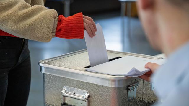 Eine Frau steckt ihren Stimm-Zettel für die Bundestags-Wahl in einen Wahl-Behälter.