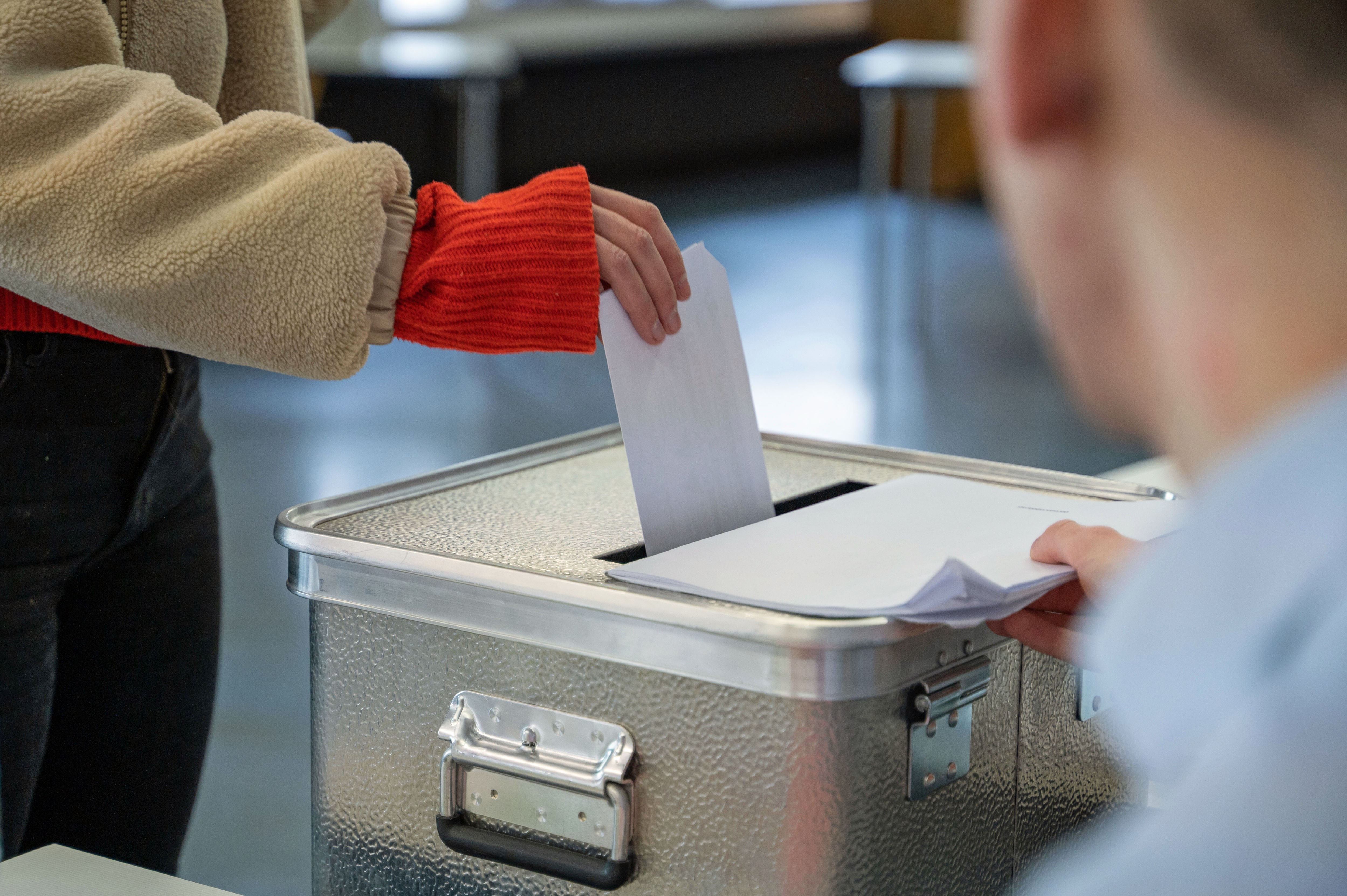 Eine Frau steckt ihren Stimmzettel für die Bundestagswahl in einem Wahllokal in eine Wahlurne. 