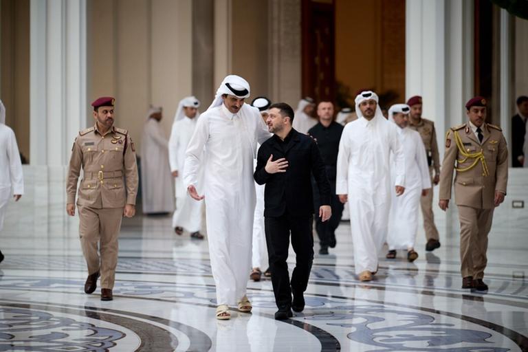 Der ukrainische Präsident Selenskyj und der Emir von Katar unterhalten sich in einer großen Halle.