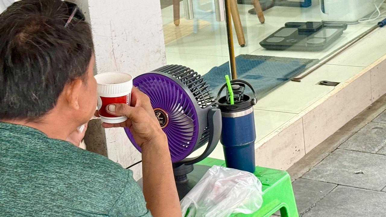 Ein Mann erfrischt sich bei Hitze an einem Ventilator. Seit Wochen ist es in Thailand ungewöhnlich heiß. Die Behörden haben mittlerweile "Cooling Centers" (Kühlzentren) eingerichtet, wo Menschen Erleichterung finden können.