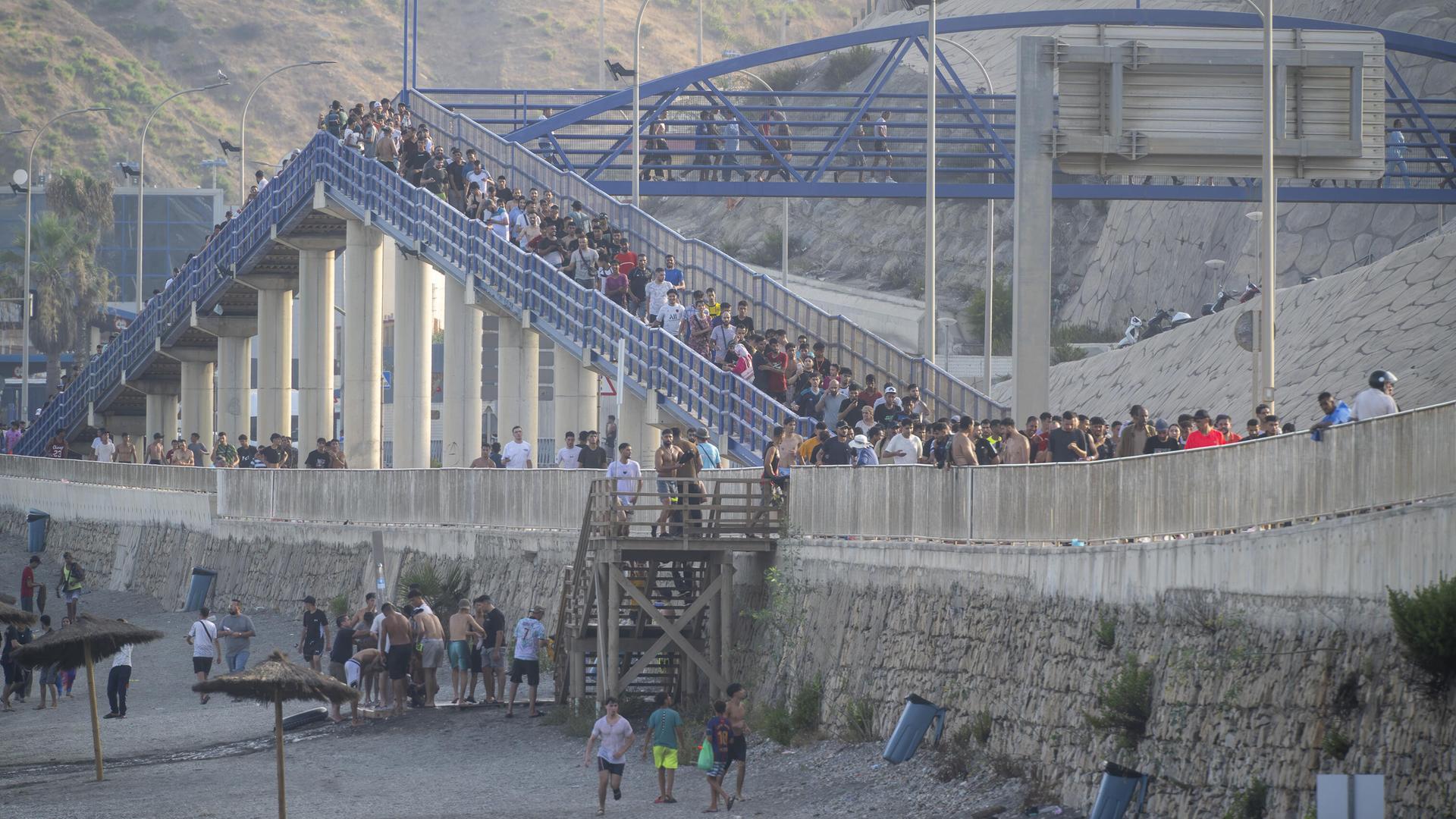 Tausende Migranten gehen entlang der Mole in Ceuta.