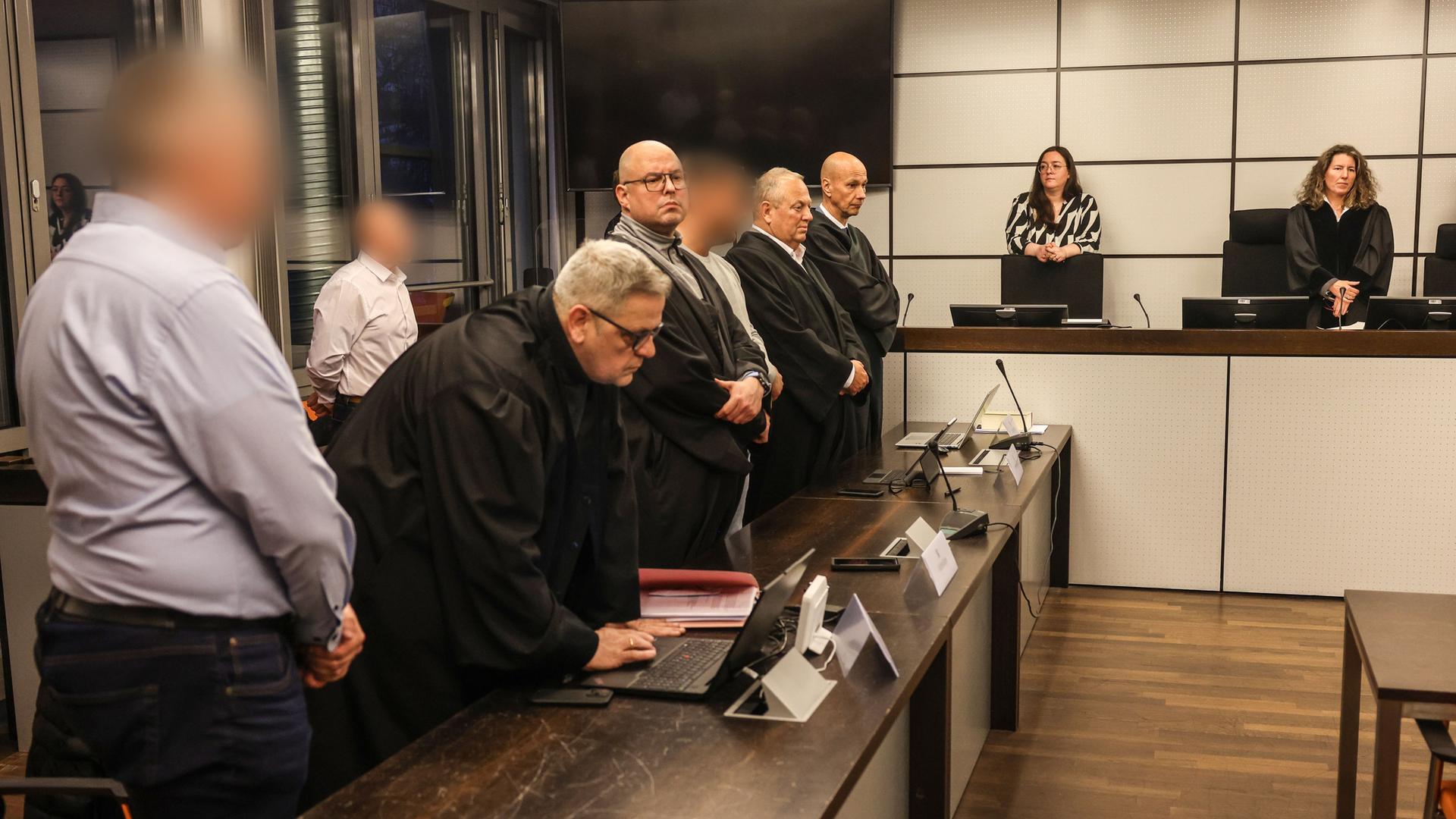 Wuppertal: Die drei Angeklagten (l, hinten l sowie 4.v.l) stehen vor der Urteilsverkündung im Gerichtssaal des Amtsgerichts zwischen Anwälten. Wuppertal: Die drei Angeklagten (l, hinten l sowie 4.v.l) stehen vor der Urteilsverkündung im Gerichtssaal des Amtsgerichts zwischen Anwälten.