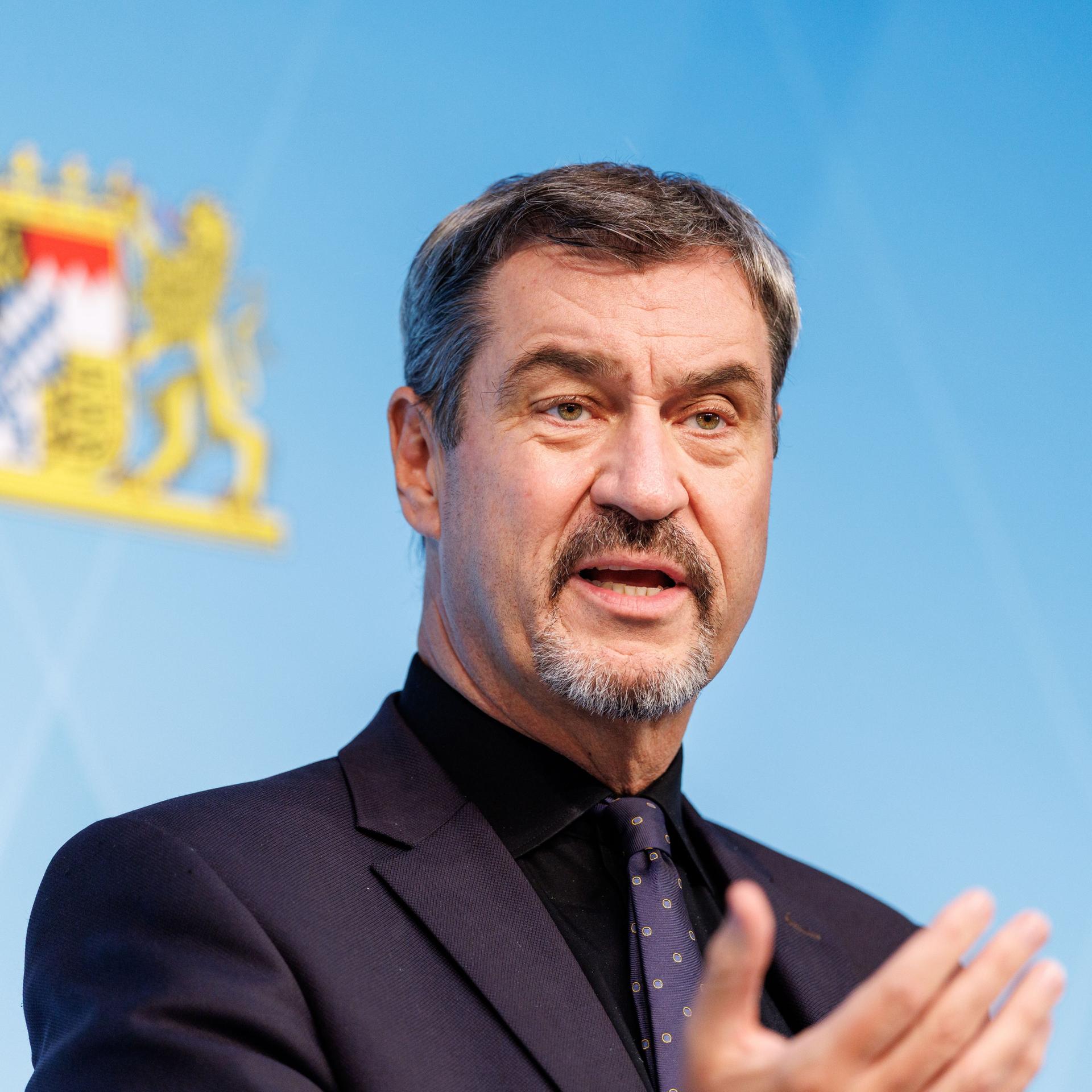 Markus Söder spricht auf einer Pressekonferenz, im Hintergrund: das Bayerische Landeswappen.