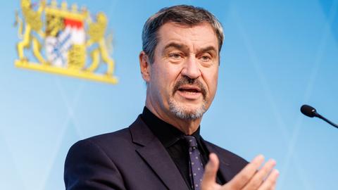 Markus Söder spricht auf einer Pressekonferenz, im Hintergrund: das Bayerische Landeswappen.