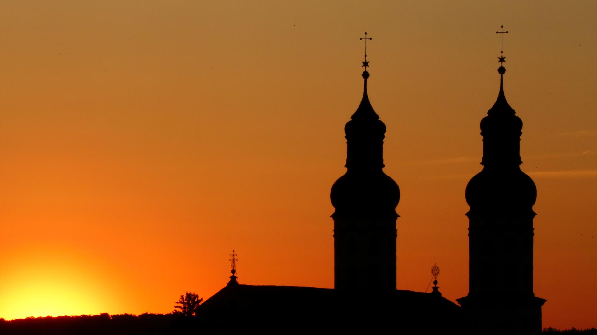 Neben den Türmen am Münster "Sankt Peter und Paul" in geht am Morgen die Sonne auf.