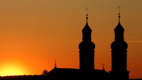 Neben den Türmen am Münster "Sankt Peter und Paul" in geht am Morgen die Sonne auf.