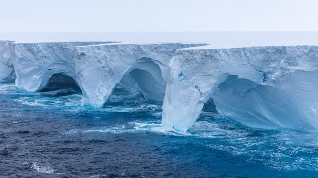 Der Eisberg schmilzt und bildet Bögen oberhalb des Wassers.