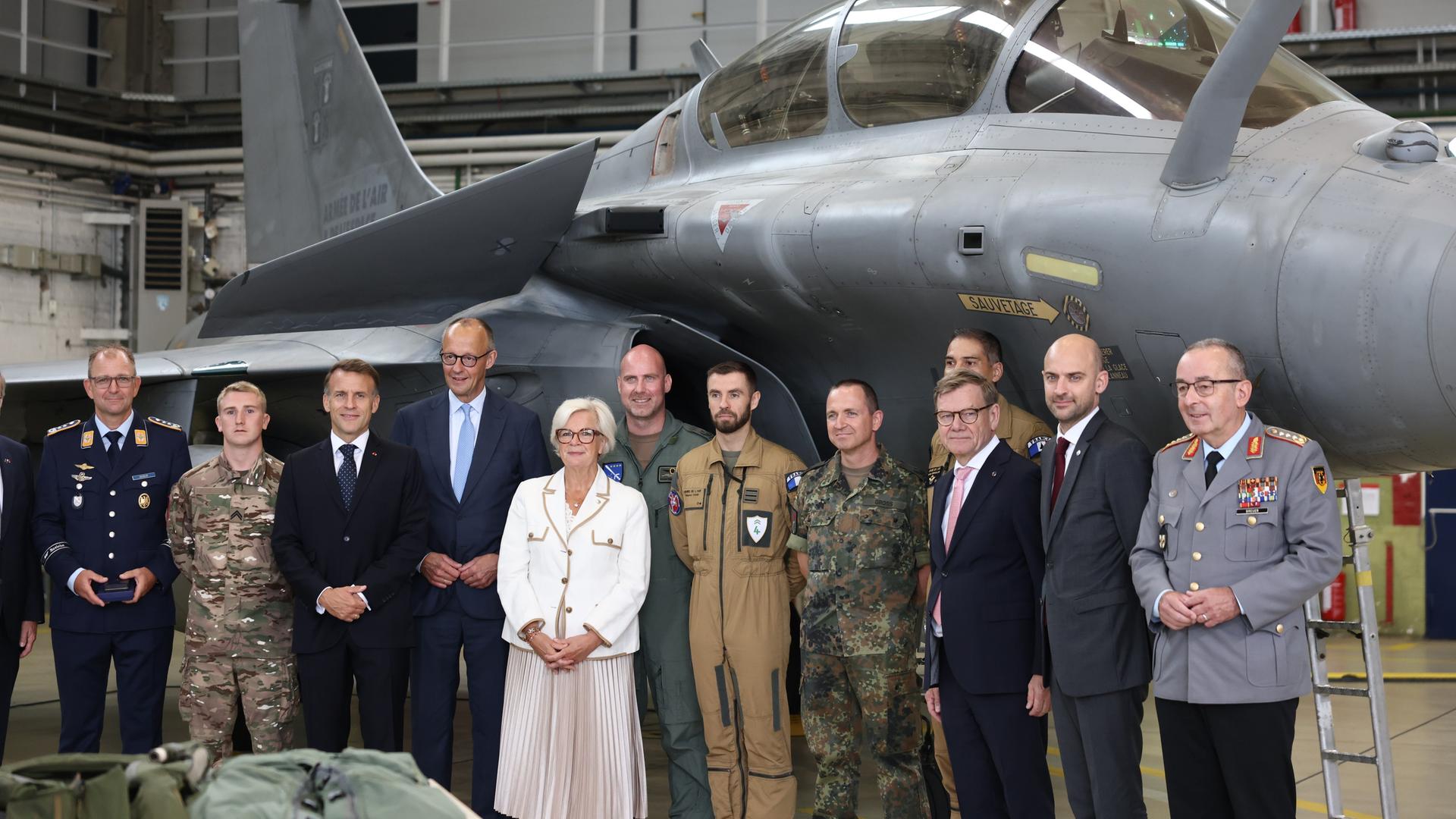 Nörvenich: Vertreter beider Länder mit Emmanuel Macron (3.vl), Präsident von Frankreich, und Bundeskanzler Friedrich Merz (4.vl, CDU), stehen vor einem Rafale-Kampfjet.