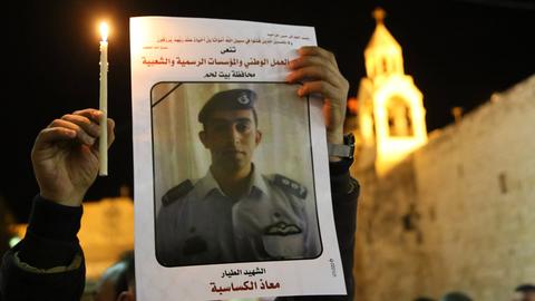 Ein Palästinenser hält am 05.02.2015 in Bethlehem eine Kerze und ein Portrait von dem vom IS ermordeten jordanischen Piloten Muath al-Kasasbeh in den Händen.