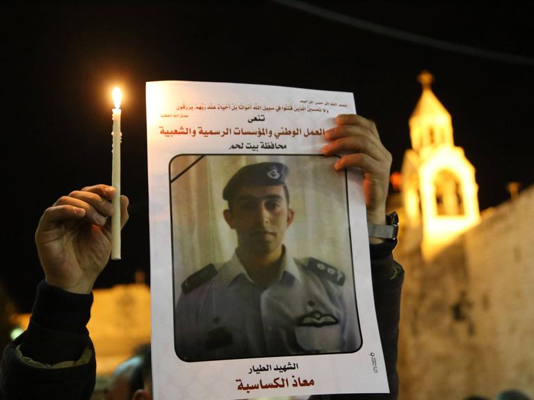 Ein Palästinenser hält am 05.02.2015 in Bethlehem eine Kerze und ein Portrait von dem vom IS ermordeten jordanischen Piloten Muath al-Kasasbeh in den Händen.